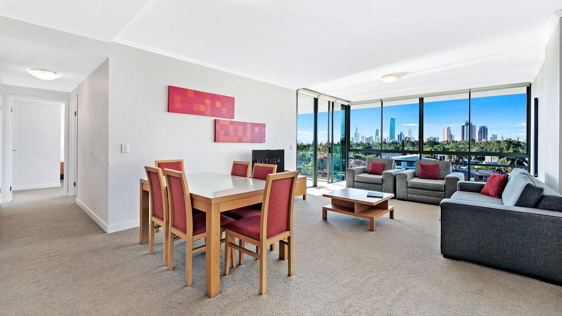 Spacious living and dining area in the 2 Bedroom Apartment at ULTIQA Freshwater Point Resort, featuring skyline views and full-length windows.