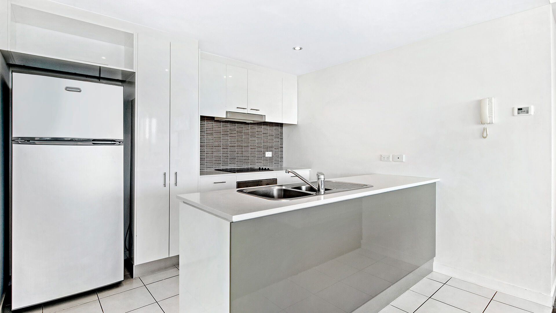 Modern kitchen in the 2 Bedroom Apartment at ULTIQA Freshwater Point Resort, featuring a full-size fridge, stovetop, oven, and ample storage.