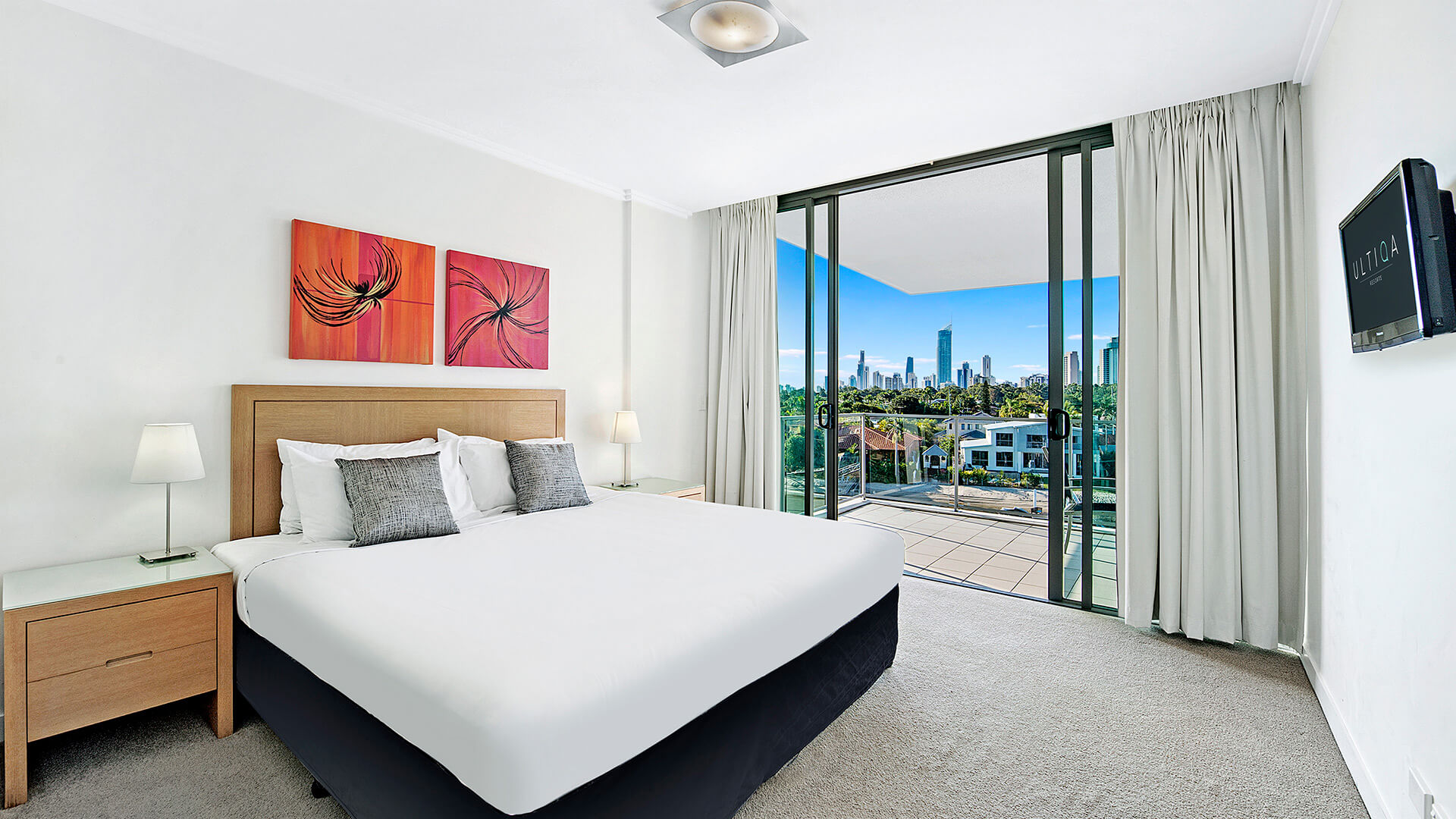 Master bedroom in the 2 Bedroom Apartment at ULTIQA Freshwater Point Resort, featuring a king bed, balcony access, and skyline views.