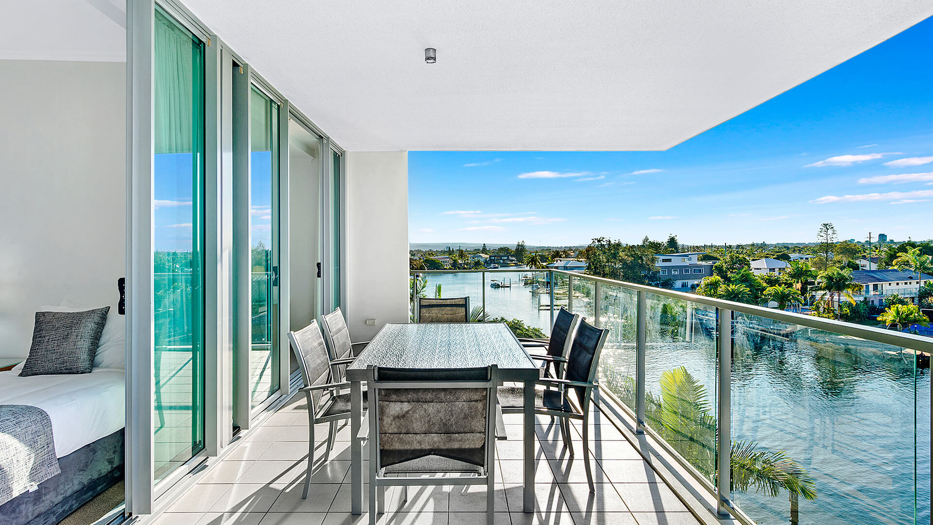 Private balcony of the 2 Bedroom Apartment at ULTIQA Freshwater Point Resort, featuring an outdoor dining setting and stunning waterway views.
