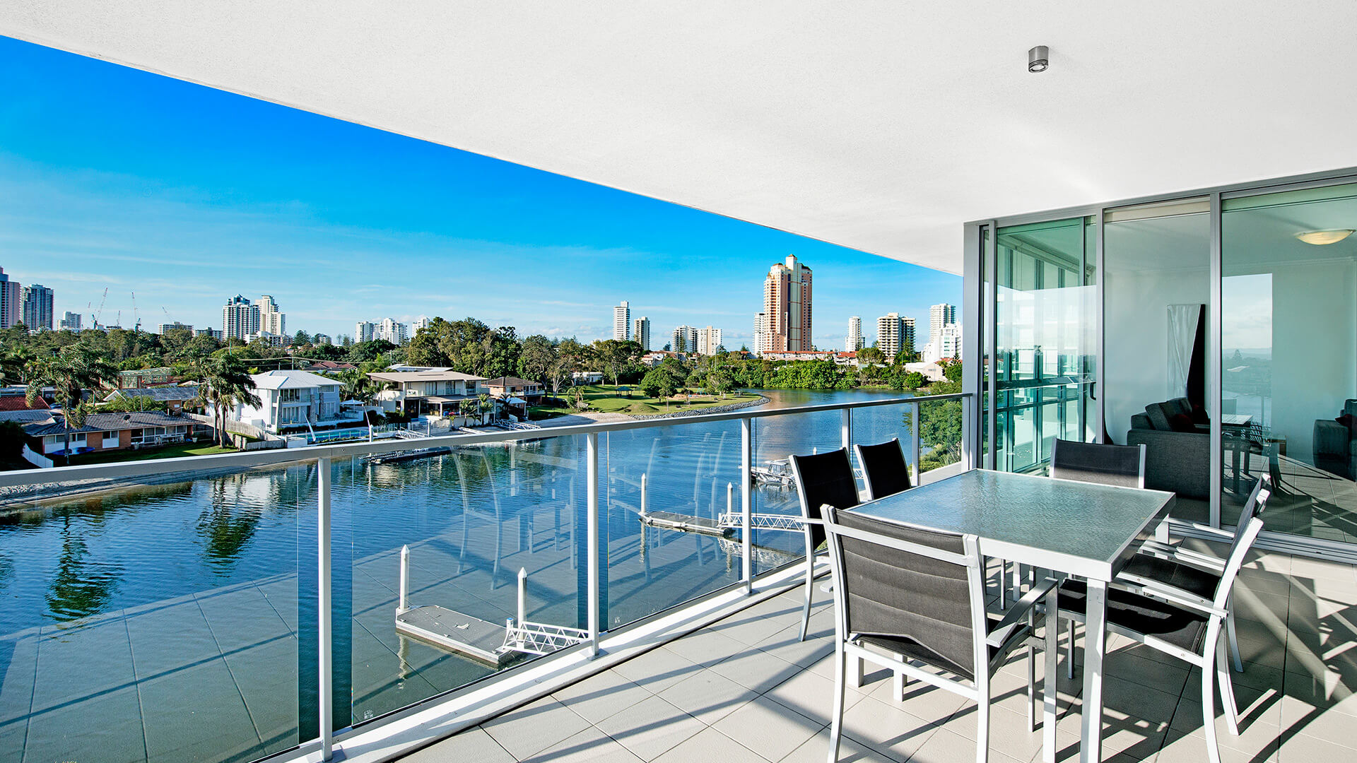 Private balcony of the 2 Bedroom Apartment at ULTIQA Freshwater Point Resort, showcasing skyline and waterway views with outdoor seating for six.