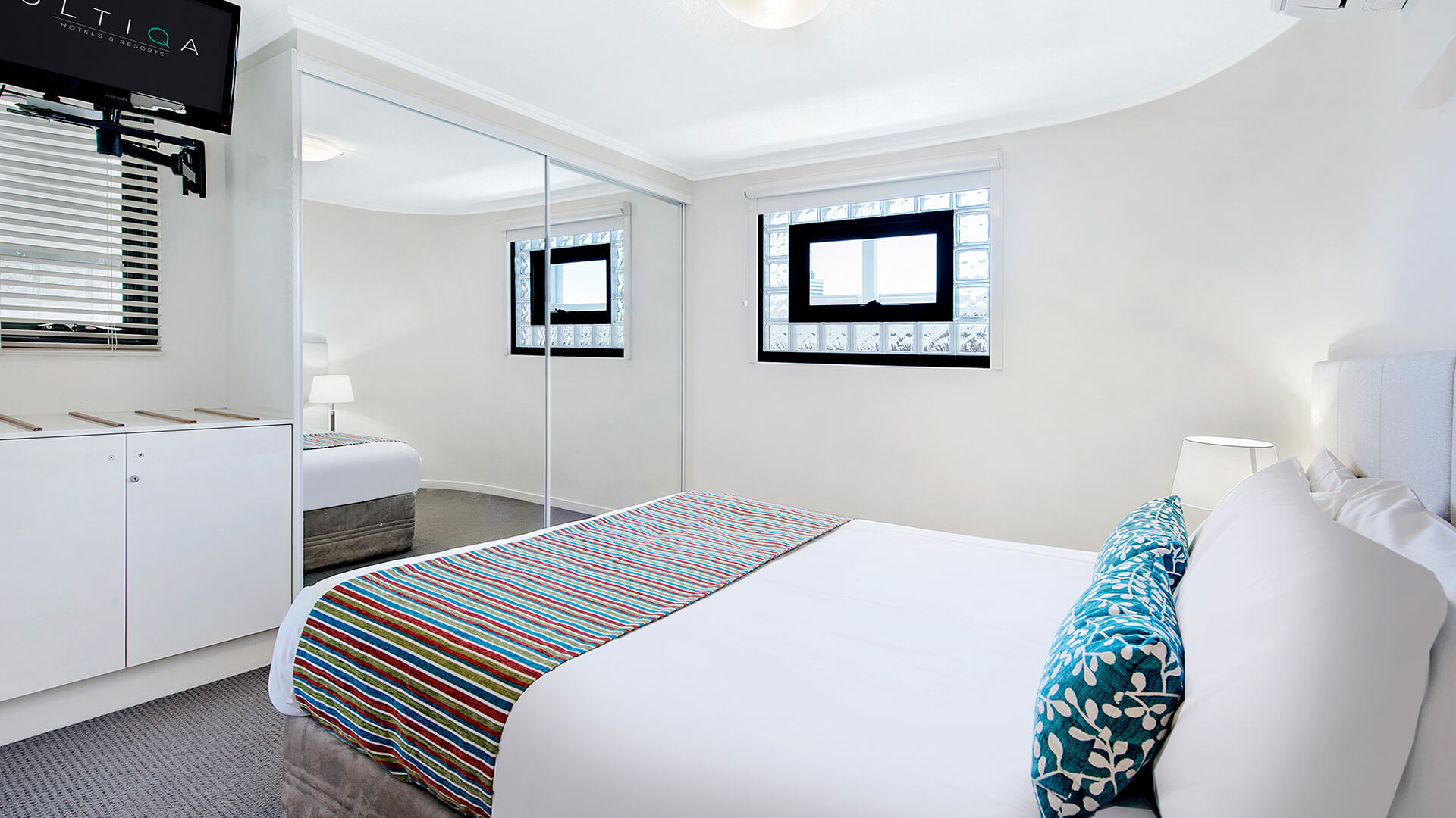Bedroom with mirrored wardrobe and TV in 2 Bedroom 1 Bathroom Apartment at ULTIQA Shearwater Resort.