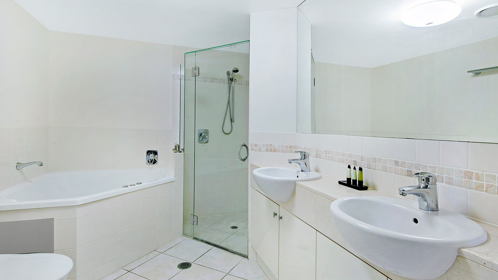 Bathroom with dual sinks, shower, and spa bath in 2 Bedroom 1 Bathroom Apartment at ULTIQA Shearwater Resort.