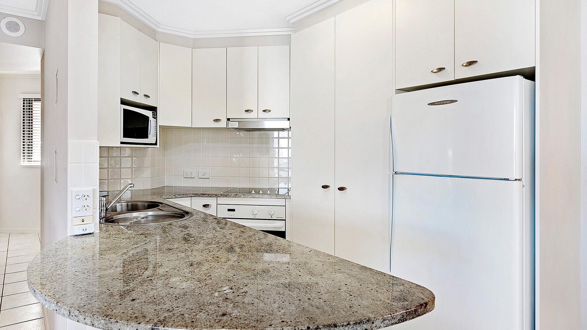 Granite benchtop kitchen with modern appliances in 3 Bedroom Dual Key Apartment at ULTIQA Shearwater Resort.