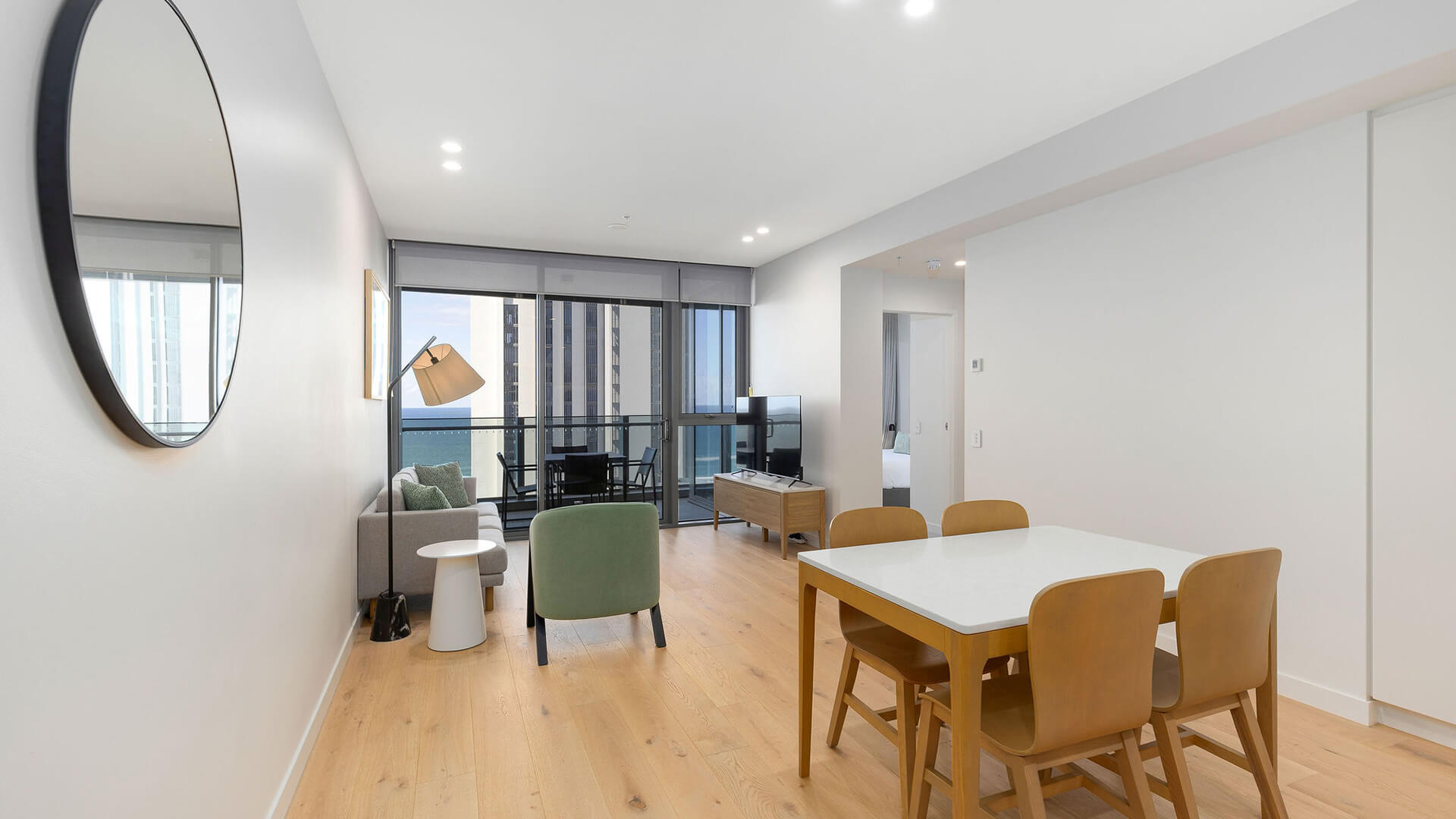 Dining and living area with ocean-view balcony in 1 Bedroom Ocean View Suite at ULTIQA Signature at Broadbeach.