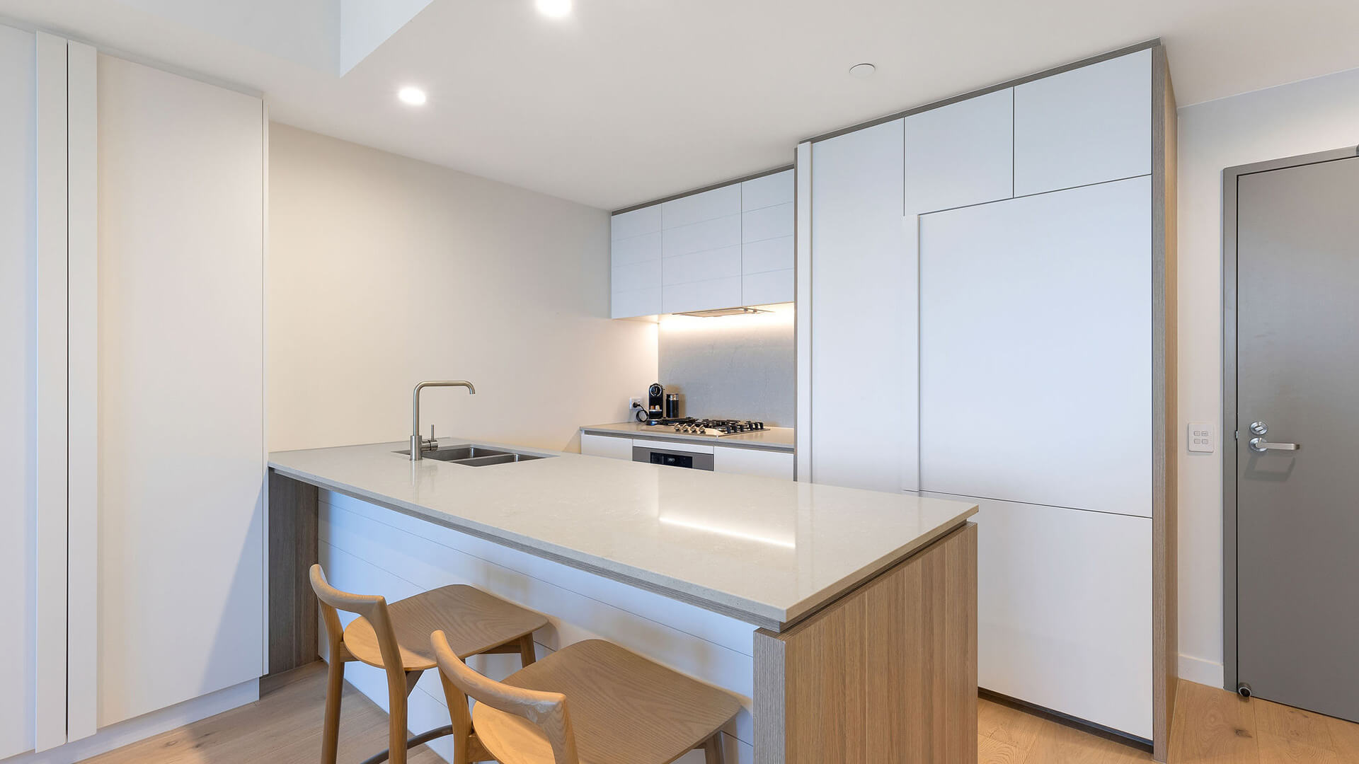 Modern kitchen with island bench and seating in 1 Bedroom Ocean View Suite at ULTIQA Signature at Broadbeach.