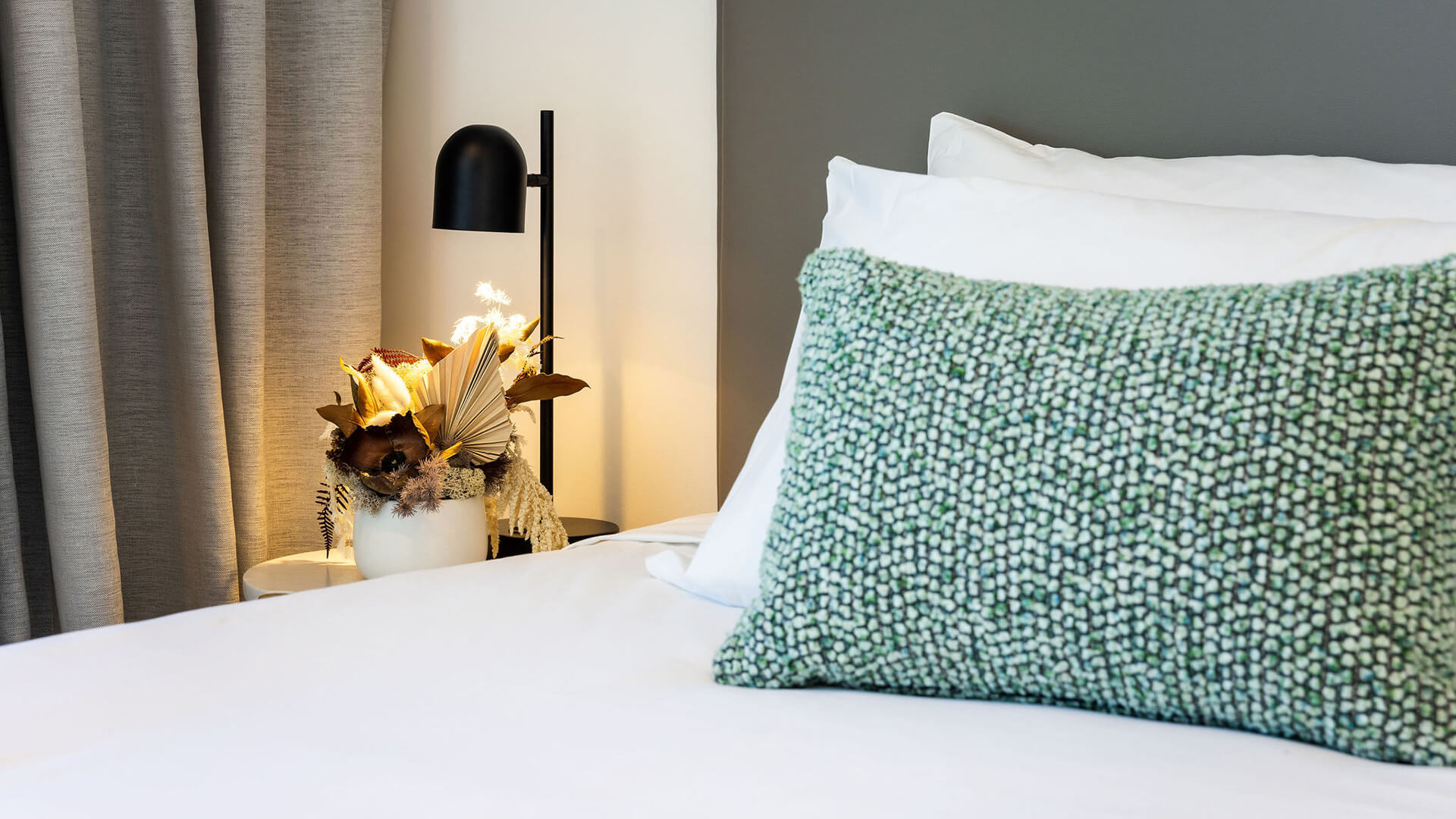 Close-up of bed with green cushion in 2 Bedroom Ocean View Suite Premium at ULTIQA Signature at Broadbeach.