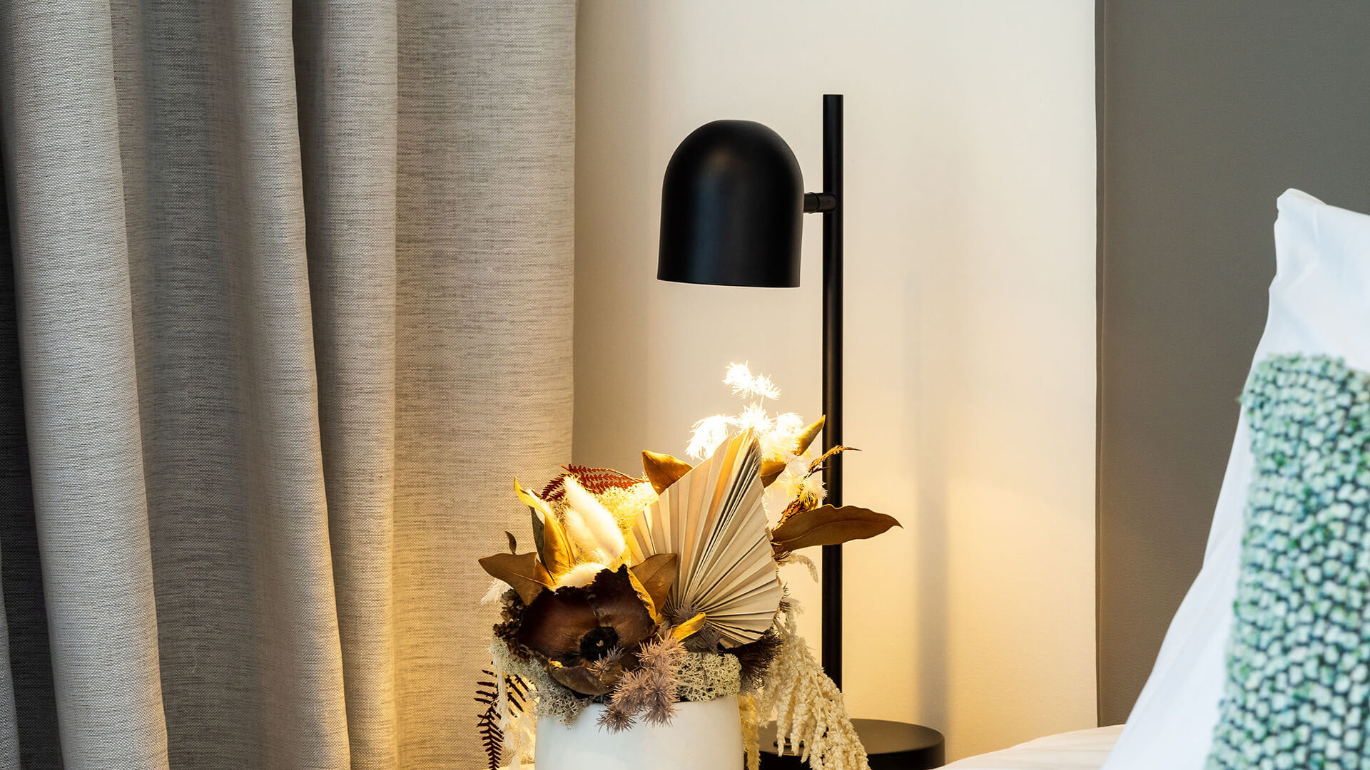 Bedside table with lamp and floral arrangement in 2 Bedroom Ocean View Suite Premium at ULTIQA Signature at Broadbeach.
