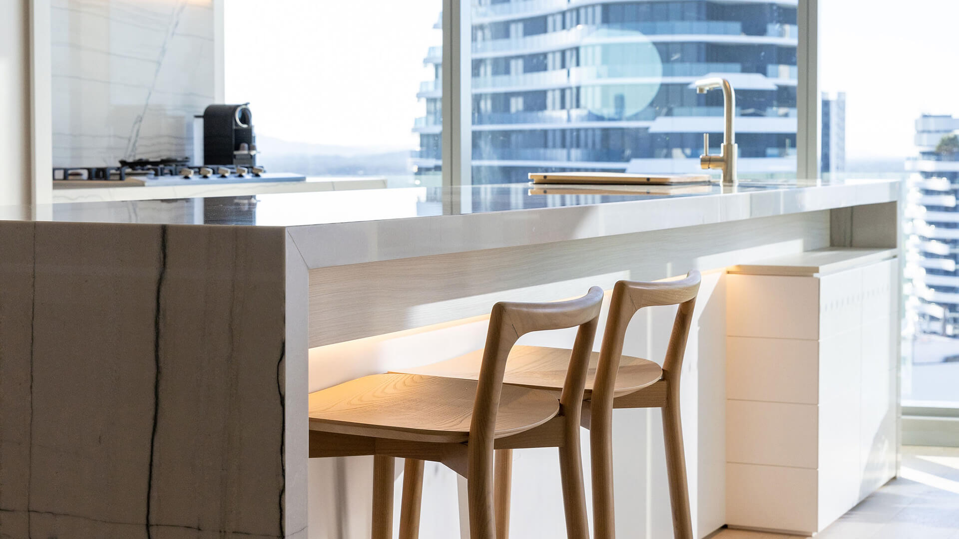Kitchen island with seating in the 3 Bedroom Ocean View Suite at ULTIQA Signature at Broadbeach, offering scenic city views.